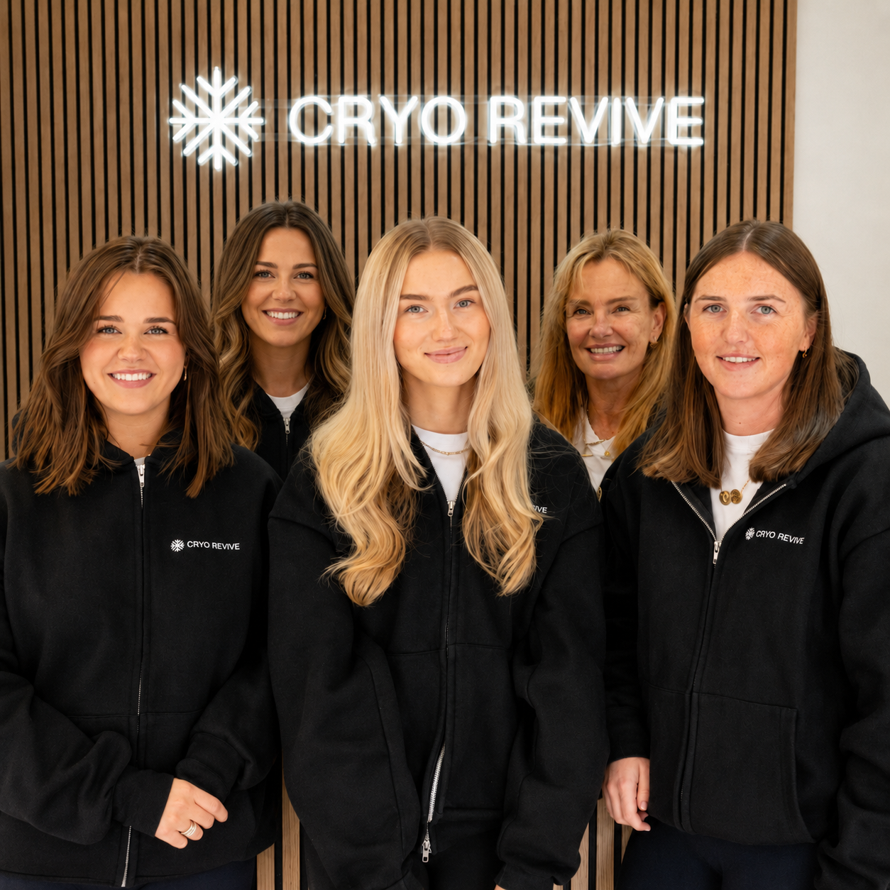 The Cryo Revive therapist team in front of the illuminated Cryo Revive sign at the studio