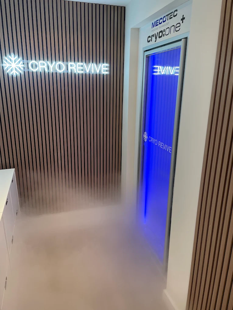 The Mecotec cryo:one chamber at the Cryo Revive studio, lit blue beside the illuminated Cryo Revive sign